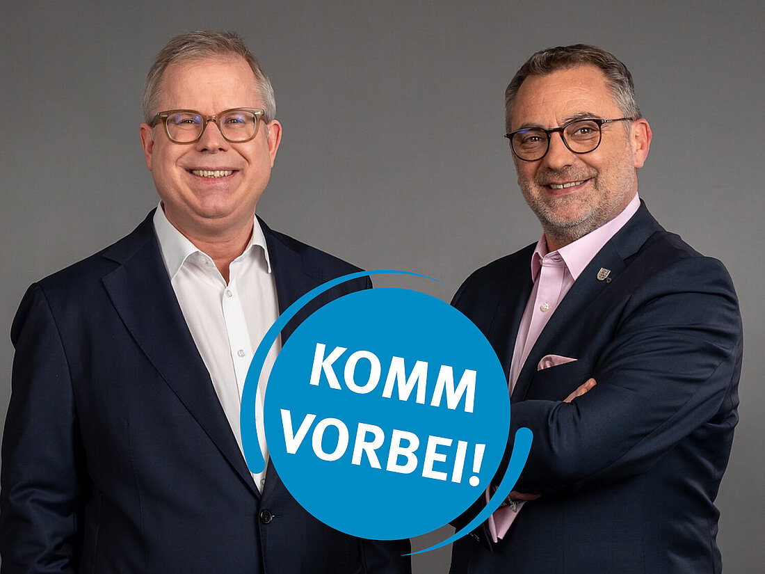 Staatssekretäre Birger Scholz und Julian Vonarb mit einem Sticker mit der Aufschrift "Komm vorbei"