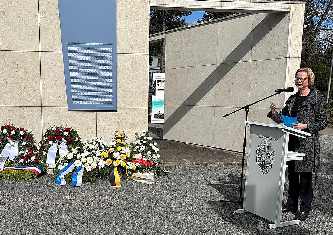 Thüringens Vize-Ministerpräsidentin und Finanzministerin Katja Wolf am Rednerpult, im Hintergrund sind viele Blumenkränze zu sehen