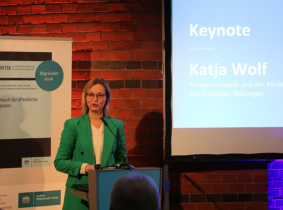 Finanzministerin Katja Wolf steht am Rednerpult und hält die Keynote zur Präsentation des Jahrbuchs für öffentliche Finanzen
