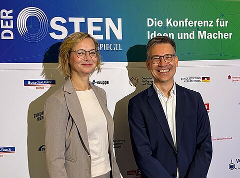 Thüringer Finanzministerin Katja Wolf steht gemeinsam mit Tagesspiegel-Chefredakteur Christian Tretbar vor einem Aufsteller für die Konferenz "Der Osten".