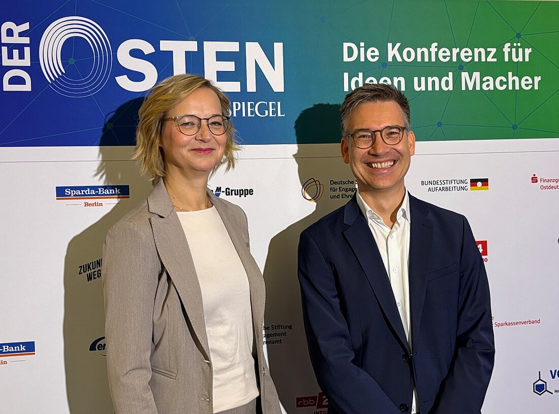 Thüringer Finanzministerin Katja Wolf steht gemeinsam mit Tagesspiegel-Chefredakteur Christian Tretbar vor einem Aufsteller für die Konferenz "Der Osten".