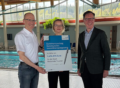 Finanzministerin Katja Wolf gemeinsam mit dem Bürgermeister der Stadt Brotterode-Trusetal Kay Goßmann und dem Vorstandsvorsitzenden der Thüringer Aufbaubank Matthias Wierlacher im Inselbergbad Brotterode-Trusetal vor dem Schwimmbecken mit einem symbolischen Darlehensvertrag in der Hand.
