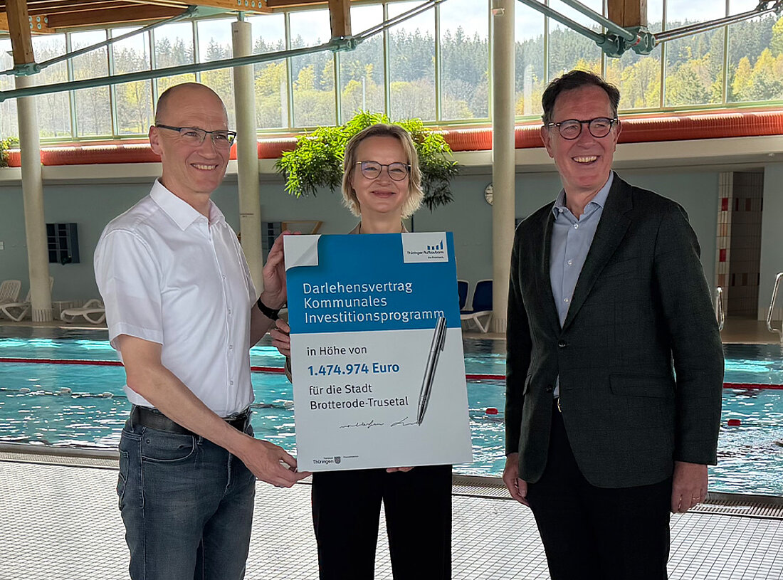 Finanzministerin Katja Wolf gemeinsam mit dem Bürgermeister der Stadt Brotterode-Trusetal Kay Goßmann und dem Vorstandsvorsitzenden der Thüringer Aufbaubank Matthias Wierlacher im Inselbergbad Brotterode-Trusetal vor dem Schwimmbecken mit einem symbolischen Darlehensvertrag in der Hand.