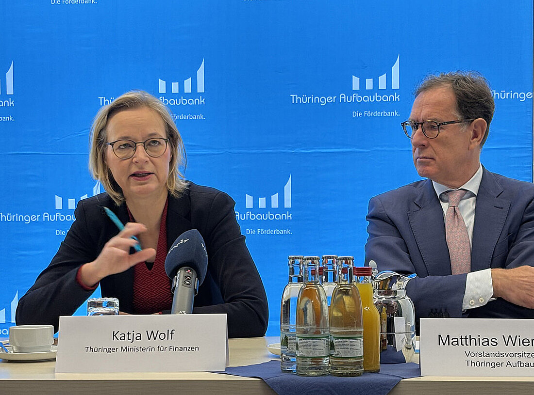Finanzministerin Katja Wolf und Vorstandsvorsitzender der Thüringer Aufbaubank sitzen an einem Tisch mit Mikrofonen