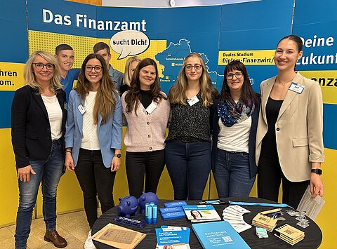 Gruppe von Vertreterinnen der Thüringer Finanzverwaltung vor dem Stand zur Nachwuchskräftegewinnung der Steuerverwaltung zum Tag der offenen Türen im Bildungszentrum in Gotha.