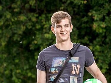 Junger Mann mit einem Handball in der Hand.