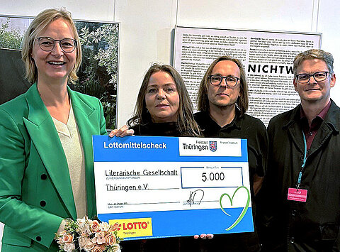 Finanzministerin Katja Wolf mit Y. Andrä und S. Petermann sowie dem Präsidenten der Literarischen Gesellschaft G. Naschert. In der Hand hält sie einen symbolischen Lottomittelscheck über 5.000 Euro.
